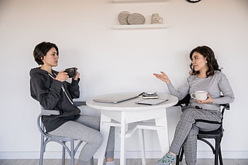 Two women enjoying a casual conversation with coffee in a cozy indoor setting, enhancing connections. HD wallpaper