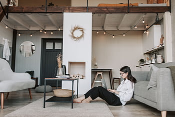 Cozy loft apartment with a woman working on a laptop, showcasing modern remote work lifestyle. HD wallpaper