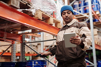 A warehouse employee scans items using a tablet, ensuring inventory accuracy. HD wallpaper