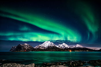 Breathtaking view of aurora borealis illuminating the snowy mountains of Lofoten Islands at night. HD wallpaper