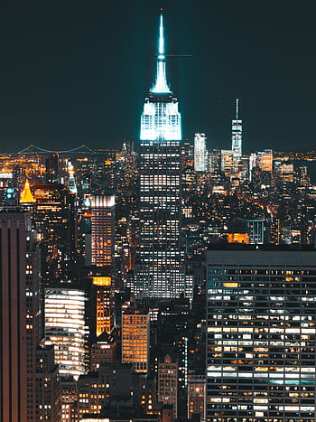 Stunning view of the Empire State Building illuminated amidst the New York City skyline at night. HD phone wallpaper
