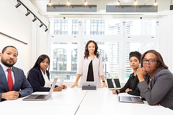 A diverse group of professionals having a meeting in a modern office setting with large windows. HD wallpaper