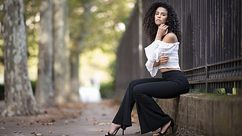 Curly Hair Girl Model Is Wearing White Top And Black Pants Sitting In Fence Background Girls HD wallpaper