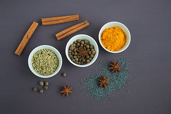 Flat lay of assorted spices including cinnamon, turmeric, and star anise on a dark surface. HD wallpaper
