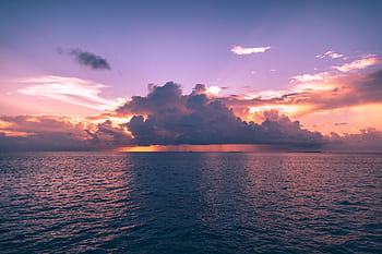 Stunning sunset view with dramatic clouds over the ocean in Maldives, perfect for travel inspiration. HD wallpaper