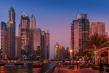 A stunning view of the Dubai Marina skyline illuminated at sunset, showcasing urban city life. HD wallpaper