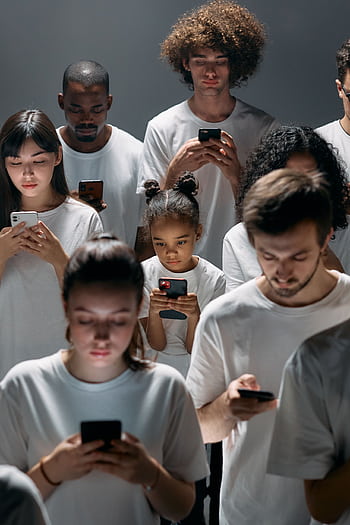 A diverse group of people focused on their smarts, symbolizing modern technology's impact on social connection. HD phone wallpaper