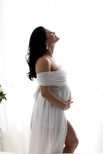 Beautiful portrait of a pregnant woman in a flowing white dress by a bright window. HD phone wallpaper