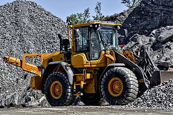 Powerful yellow construction loader moving gravel in an industrial quarry site. HD wallpaper
