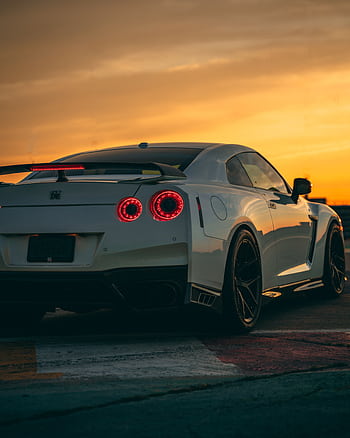 A white Nissan GT-R sports car captured at sunset in Montreal, Canada, showcasing its sleek design. HD phone wallpaper