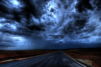 A dramatic stormy sky with dark clouds over an empty road. Nature's power captured at its peak. HD wallpaper