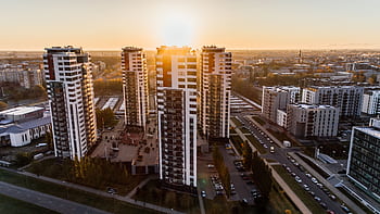 Captivating high-rise buildings silhouetted by a setting sun in a bustling cityscape. HD wallpaper
