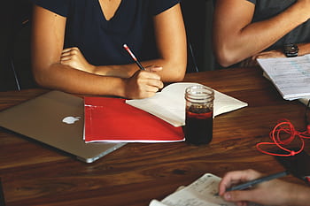 Group of adults collaborating in a modern workspace with laptops, notes, and refreshments. HD wallpaper