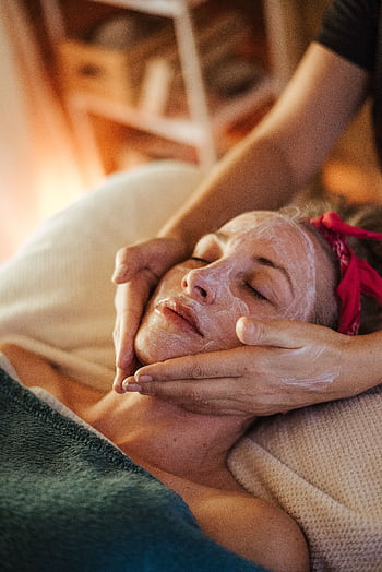 A woman enjoys a calming facial treatment, highlighting spa wellness. HD phone wallpaper