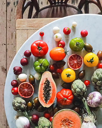 A vibrant collection of assorted fruits and vegetables displayed on a round white surface. HD phone wallpaper
