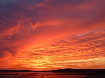 Stunning red sunset with vivid clouds reflecting over tranquil beach waters, capturing nature's beauty. HD wallpaper