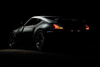 A dramatic shot of a Nissan 370Z sports car illuminated in darkness with vibrant tail lights. HD wallpaper