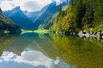 A serene mountain lake with clear reflections and lush greenery, perfect for nature enthusiasts. HD wallpaper