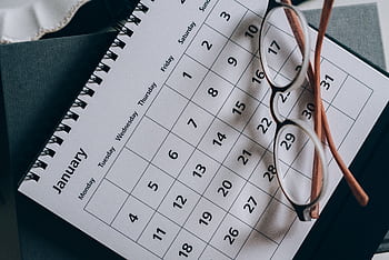 A close-up of a January calendar with eyeglasses on a table, emphasizing planning and organization. HD wallpaper