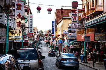 Bustling Chinatown street with hanging lanterns, shops, and vehicles. HD wallpaper