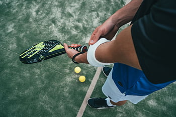 Close-up of a male padel player adjusting wristband on a court. Sports action focused. HD wallpaper