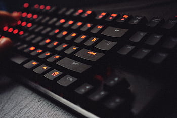 Detailed view of a gaming keyboard with backlit keys and glowing red lights. HD wallpaper