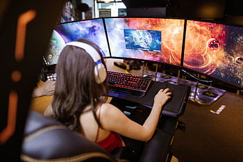 Woman with heads playing on a multi-screen gaming setup featuring vibrant space ry. HD wallpaper
