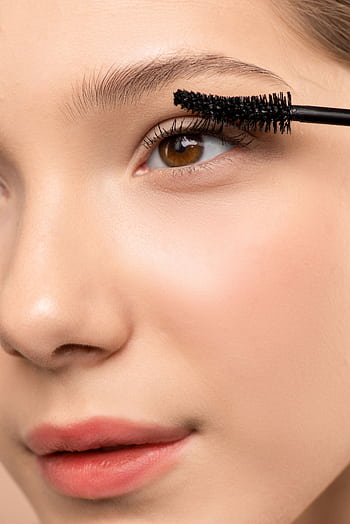 Detailed close-up of a woman applying mascara to emphasize lashes and eye beauty. HD phone wallpaper