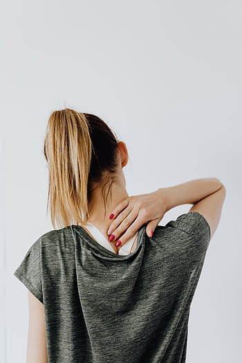 Woman in casual wear holding neck, showing signs of discomfort or pain. HD phone wallpaper