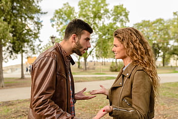 A couple having an argument outdoors, expressing frustration and conflict. HD wallpaper