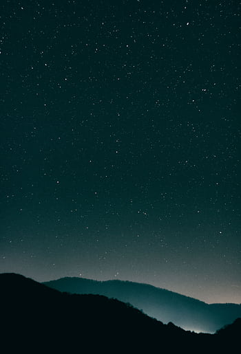 A scenic view of a starry night sky above serene mountains, offering tranquility. HD phone wallpaper