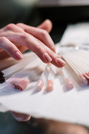 Close-up of a woman's hand selecting nail polish colors in a beauty salon. HD phone wallpaper