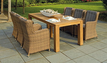 A serene outdoor patio set up with rattan chairs and a wooden table, perfect for relaxation. HD wallpaper