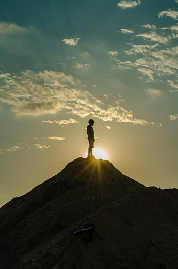 A silhouette of a person standing on a peak during a stunning sunset, capturing the essence of adventure and awe. HD phone wallpaper