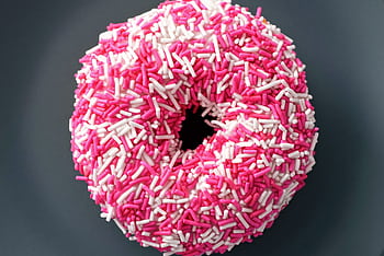 Close-up of a donut covered in pink and white sprinkles, perfect for sweet treat themes. HD wallpaper