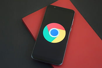 Close-up of a smart with Chrome browser logo on screen placed on a red notebook. HD wallpaper