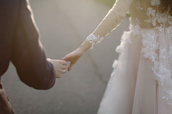 A tender moment captured of a bride and groom holding hands, symbolizing love and togetherness. HD wallpaper