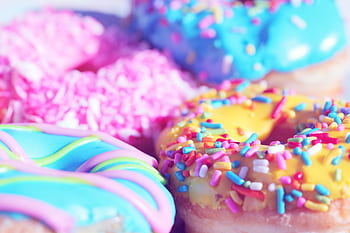 Close-up of assorted donuts with colorful icing and sprinkles, showcasing sweet indulgence. HD wallpaper