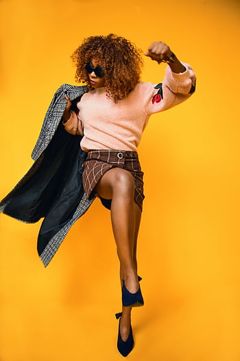 Stylish woman in a dynamic fashion pose against a vibrant orange background. HD phone wallpaper