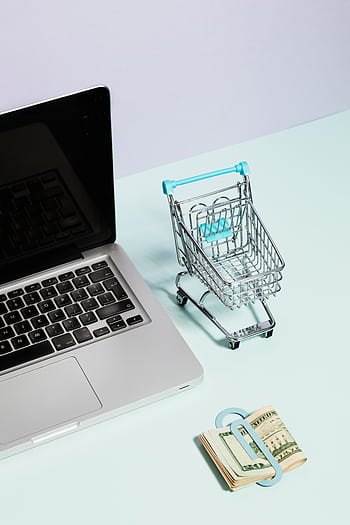 Laptop and mini shopping cart with cash representing online shopping and e-commerce. HD phone wallpaper