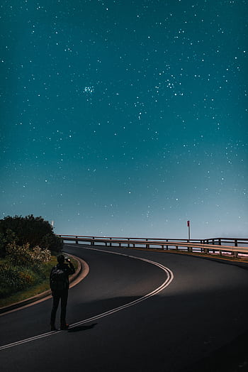 A lone traveler gazes at a breathtaking starry sky on a quiet road in Byron Bay. HD phone wallpaper