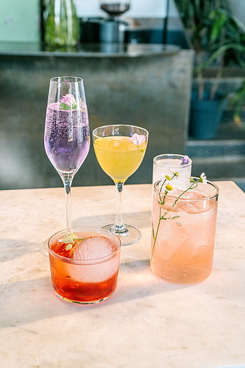 A vibrant selection of cocktails garnished with flowers, ideal for party and refreshment settings. HD phone wallpaper