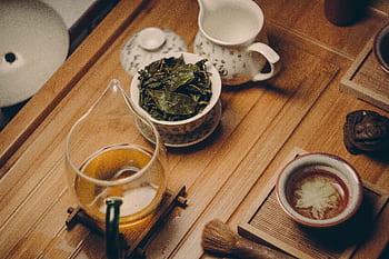 Warm, inviting tea ceremony scene with traditional teapot, leaves, and cup on a wooden table. HD wallpaper