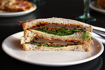 Close-up of a hearty sandwich with fresh ingredients, ready to enjoy. HD wallpaper