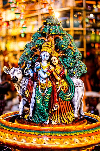 Vibrant figurine depicting Indian deities Radha and Krishna with a cow, symbolizing love and divinity. HD phone wallpaper