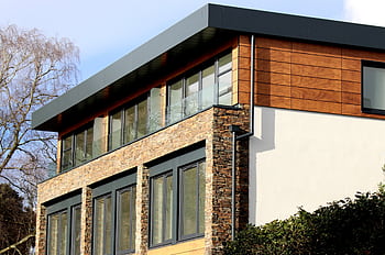 Contemporary house in Poole featuring a striking mix of stone and wood facade with large windows. HD wallpaper