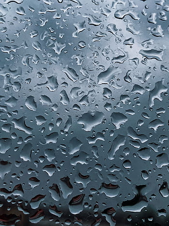 Close-up of raindrops on a glass window with a gloomy sky in the background, creating an abstract pattern. HD phone wallpaper