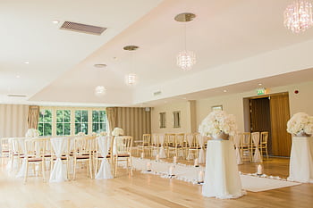 Brightly lit indoor wedding venue with elegant seating and floral decor, perfect for luxurious ceremonies. HD wallpaper