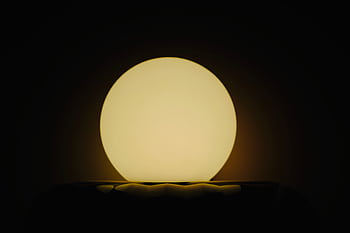 A glowing spherical lamp creates a serene ambiance in a dark setting. HD wallpaper