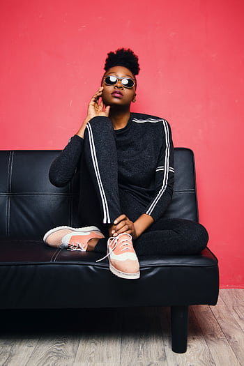 Fashionable woman posing confidently on a sofa in a modern studio setting. HD phone wallpaper
